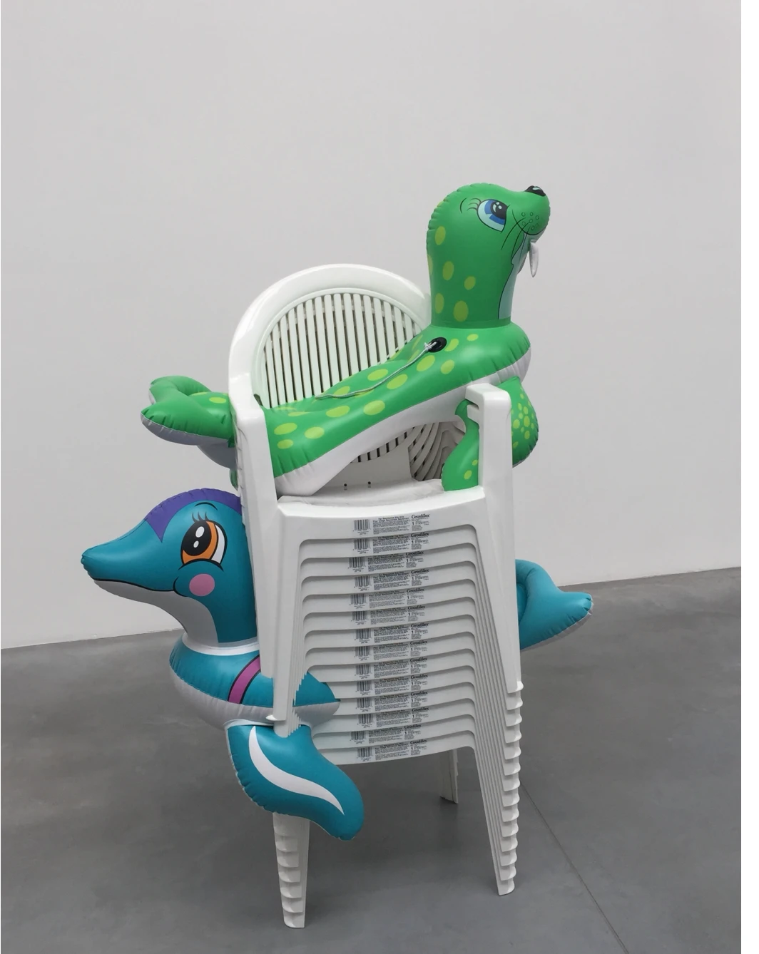 Seal and dolphin sculptures threaded through stacked white garden chairs
